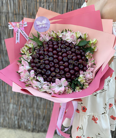 Hand-crafted Cherry Bouquet with flowers around it, wrapped in a pink wrapping paper (2 shades of pink) and with our signature butterfly