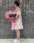 Hand-crafted Cherry Bouquet with flowers around it, wrapped in a pink wrapping paper (2 shades of pink) and with our signature butterfly