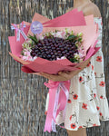 Hand-crafted Cherry Bouquet with flowers around it, wrapped in a pink wrapping paper (2 shades of pink) and with our signature butterfly